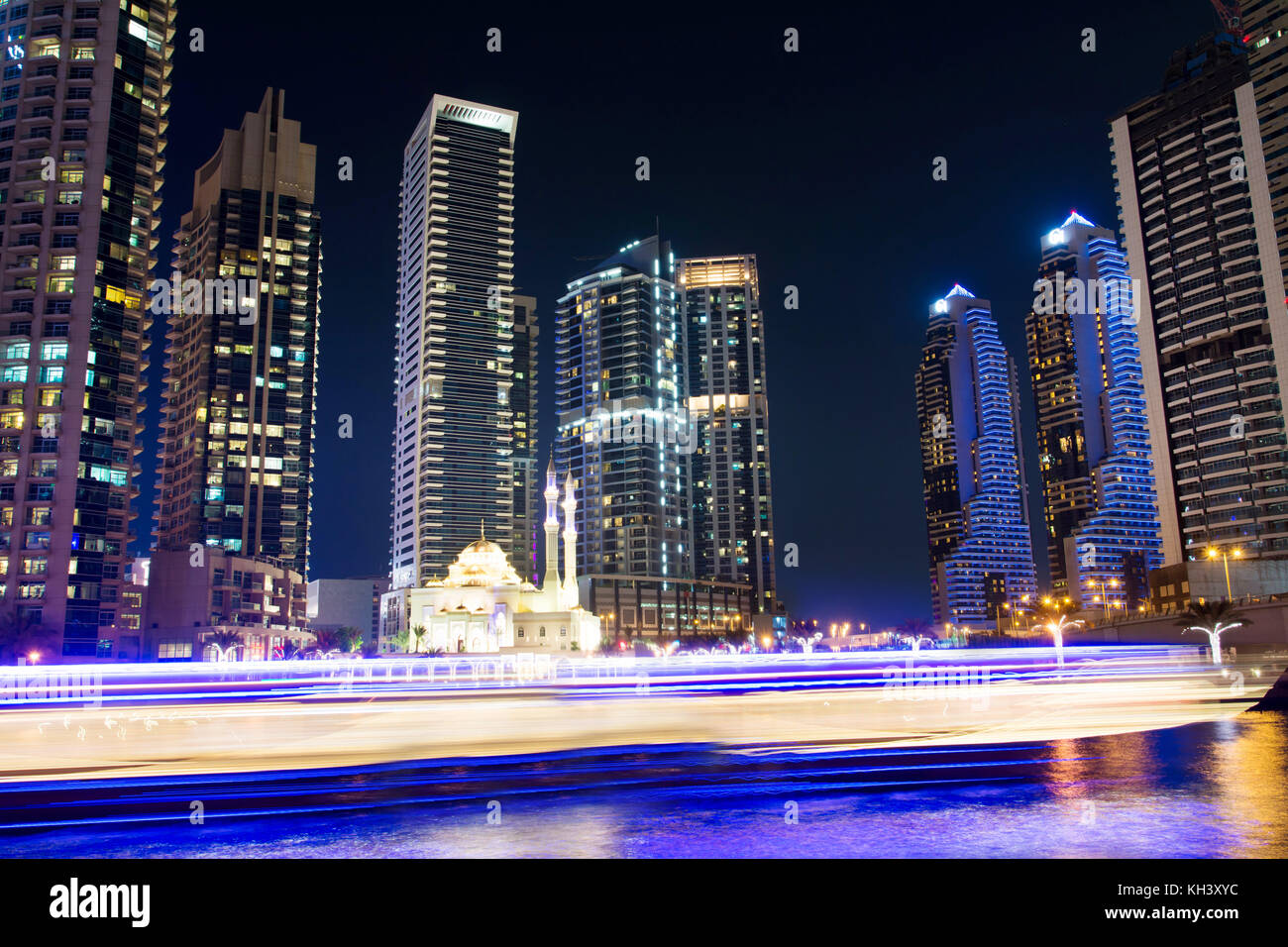 Mezquita con rascacielos de Dubai Marina y yates de estelas de luz en la noche Foto de stock
