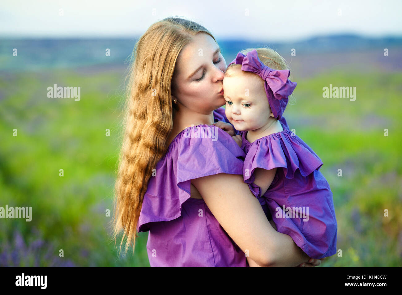 Madre e hija pequeña jugando juntos en un parque. madre besa suavemente a su pequeña hija Foto de stock