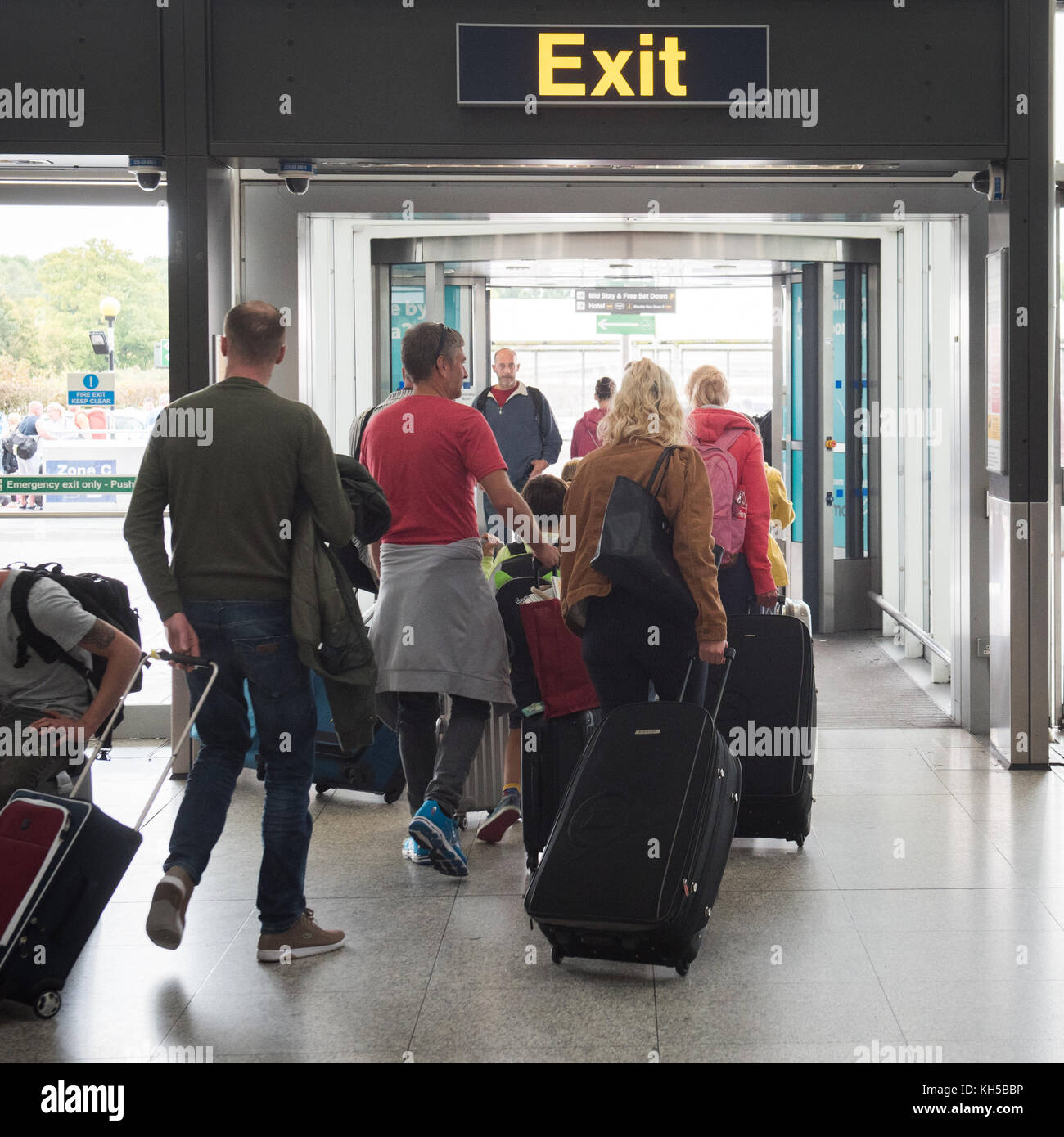 La gente dejando el aeropuerto de Stansted a través de la señal de salida de arribos internacionales. Foto de stock