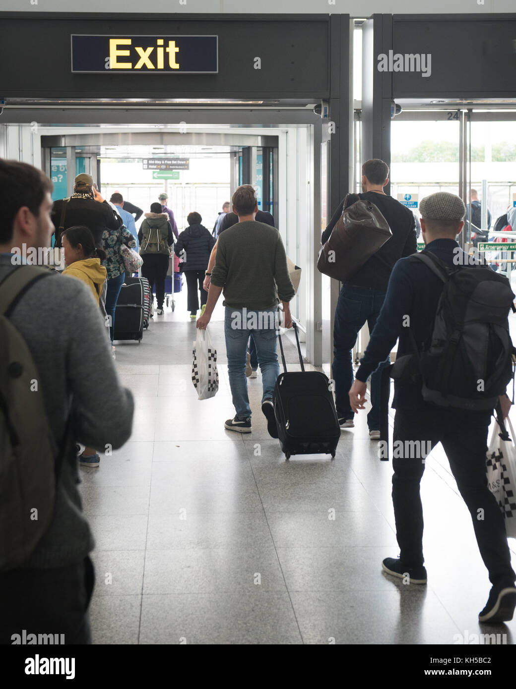 La gente dejando el aeropuerto de Stansted a través de la señal de salida de arribos internacionales. Foto de stock