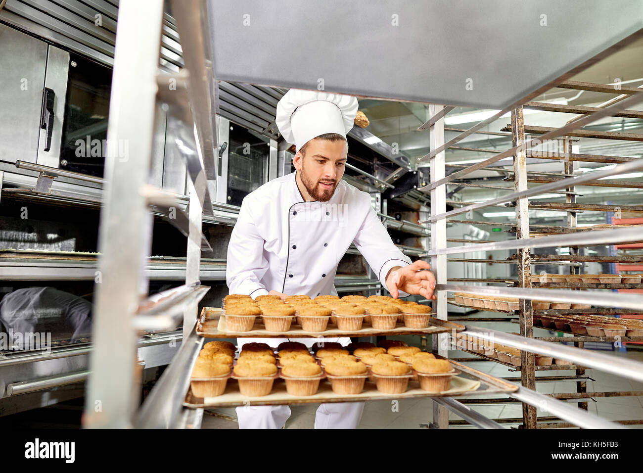 Baker hombre con una bandeja de pastelitos en sus manos a la obra en Cristo Foto de stock