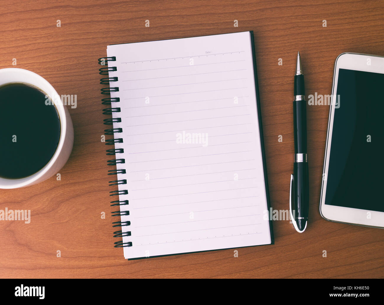 Abra el bloc de notas en blanco con café, la pluma y el teléfono inteligente. Foto de stock