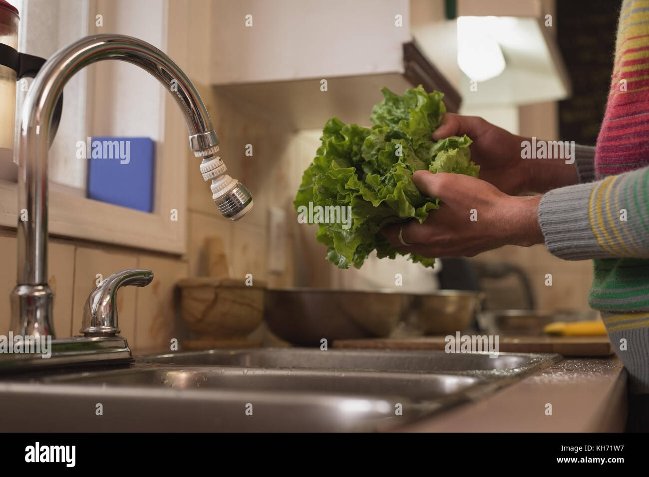 Sección intermedia del hombre lavar las verduras en la cocina Foto de stock