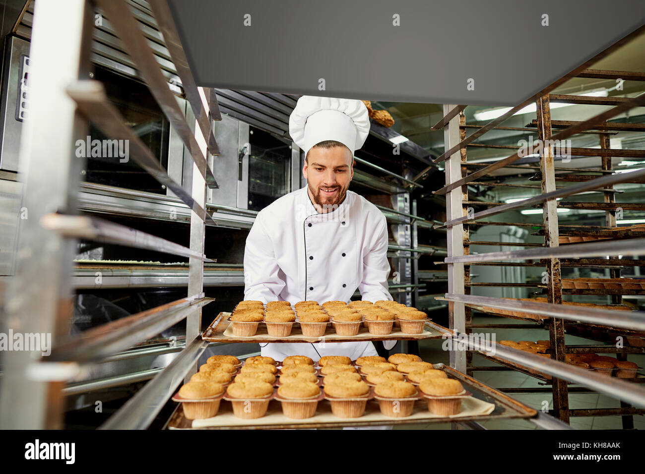 Un hombre panadero con una bandeja de pastelitos. Foto de stock