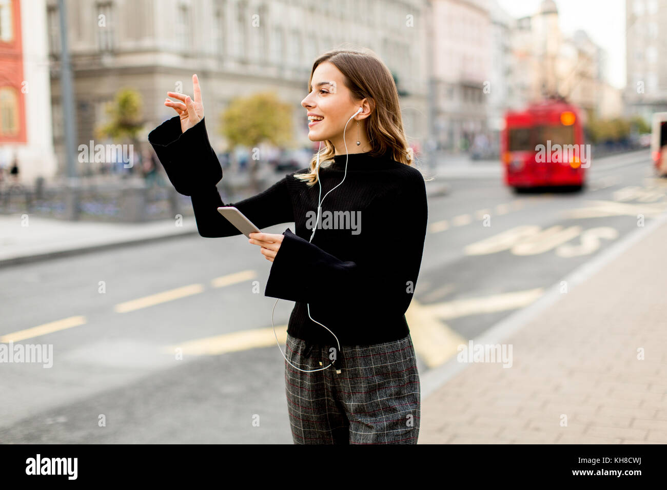 Mujer joven esperando un taxi o autobús en la calle en la ciudad Foto de stock