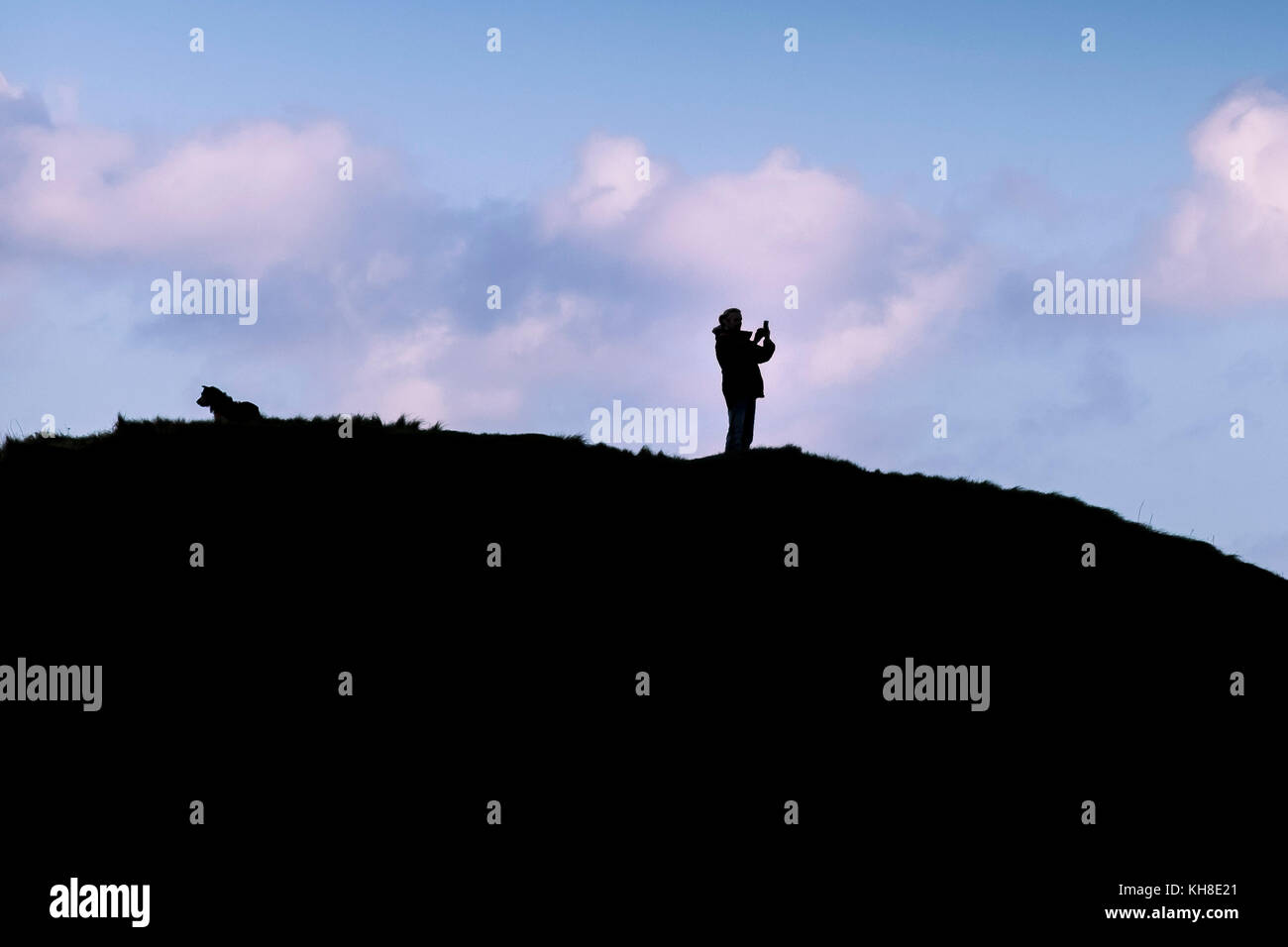 La silueta de un hombre utilizando su smartphone para fotografiar la vista. Foto de stock