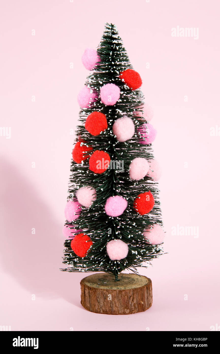 Aislado con nieve artificial completo árbol de navidad decorado con pompones  sobre un fondo de color rosa pop vibrante la fotografía de modos de vida  mínimo Fotografía de stock - Alamy