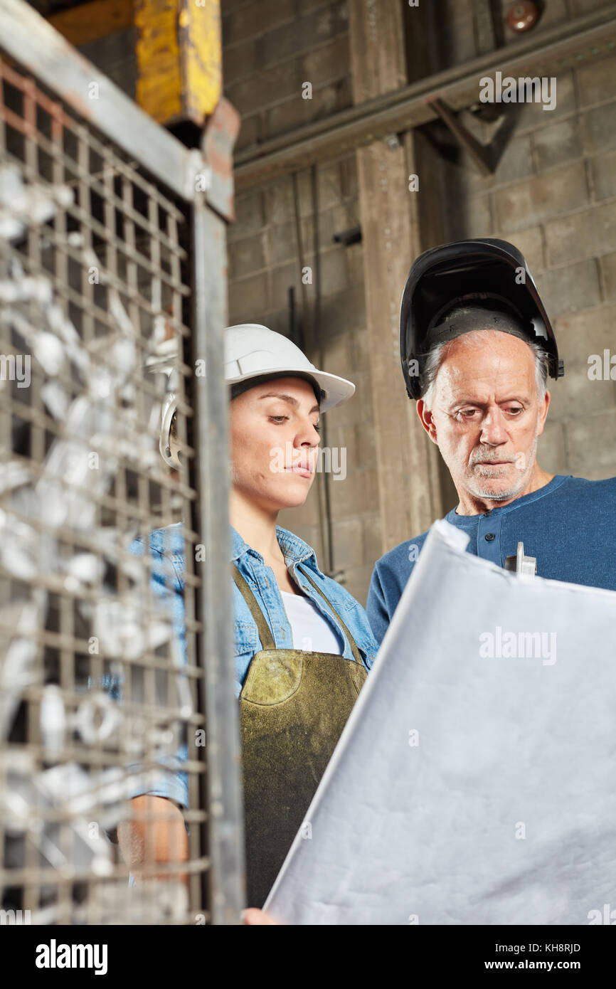 Dos trabajadores de la construcción metálica de planificación de producción en cooperación Foto de stock