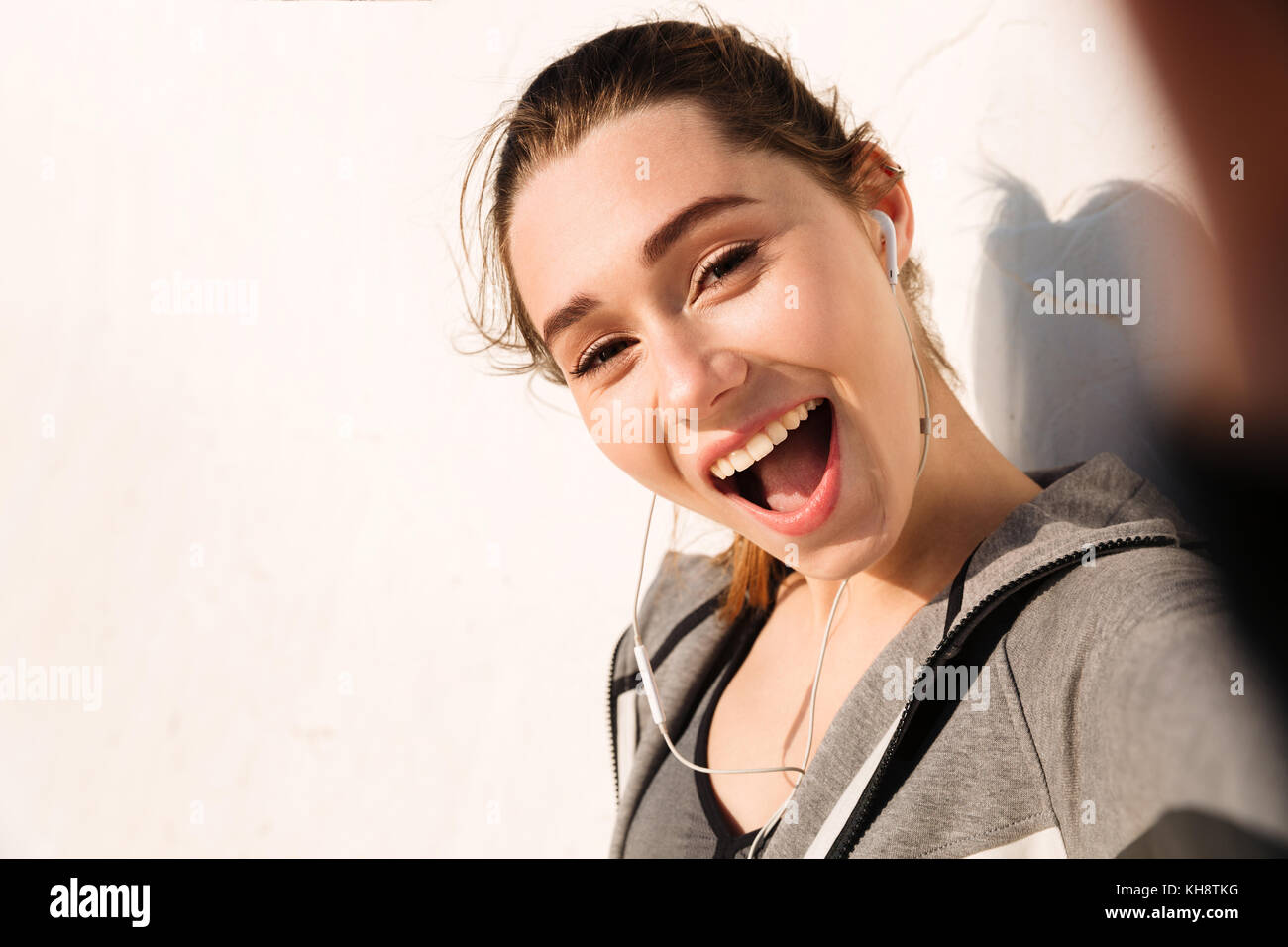 Close-up de feliz bastante joven mujer deportiva, mirando a la cámara con la boca abierta Foto de stock