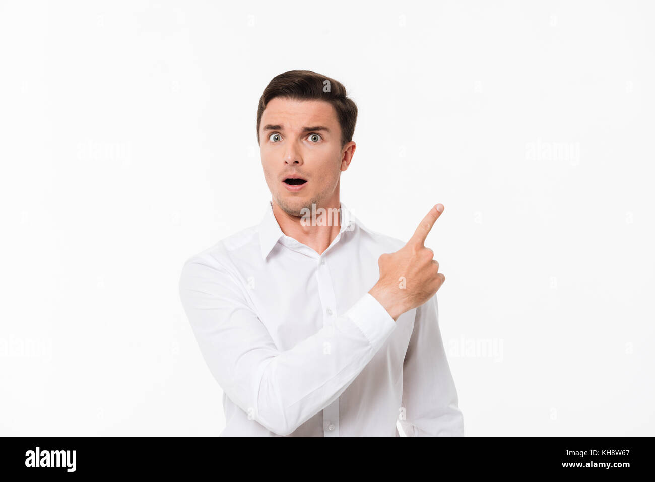 close-up-retrato-de-un-hombre-asombrado-sorprendio-en-una-camisa-blanca-de-pie-y-dedo-senalador-lejos-en-el-espacio-mientras-copia-mirando-a-la-camara-mas-aislado-kh8w67.jpg
