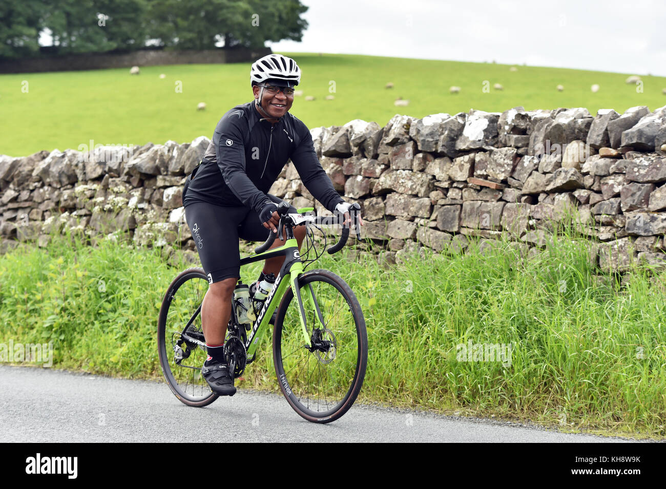 Un ciclista ciclismo en los valles de Yorkshire junto a un muro de piedra seca UK Foto de stock