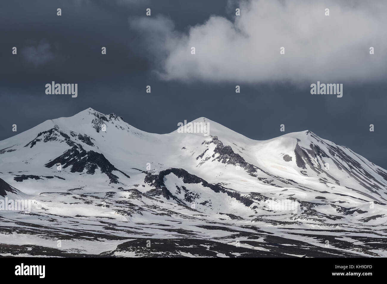 Un cielo oscuro sobre montañas nevadas en Islandia Foto de stock