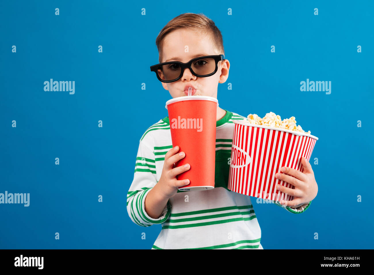 Cool Joven de anteojos preparación para ver la película mientras bebe soda  y la celebración de palomitas de maíz sobre fondo azul Fotografía de stock  - Alamy
