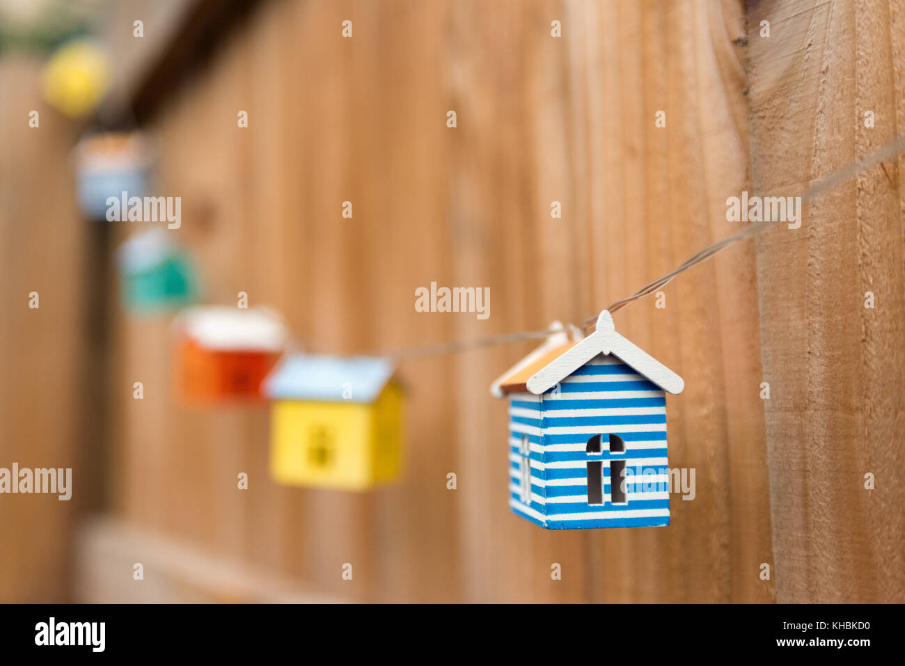 Coloridas casas modelo diminuto vinculado a una cuerda colgando de una valla. Foto de stock