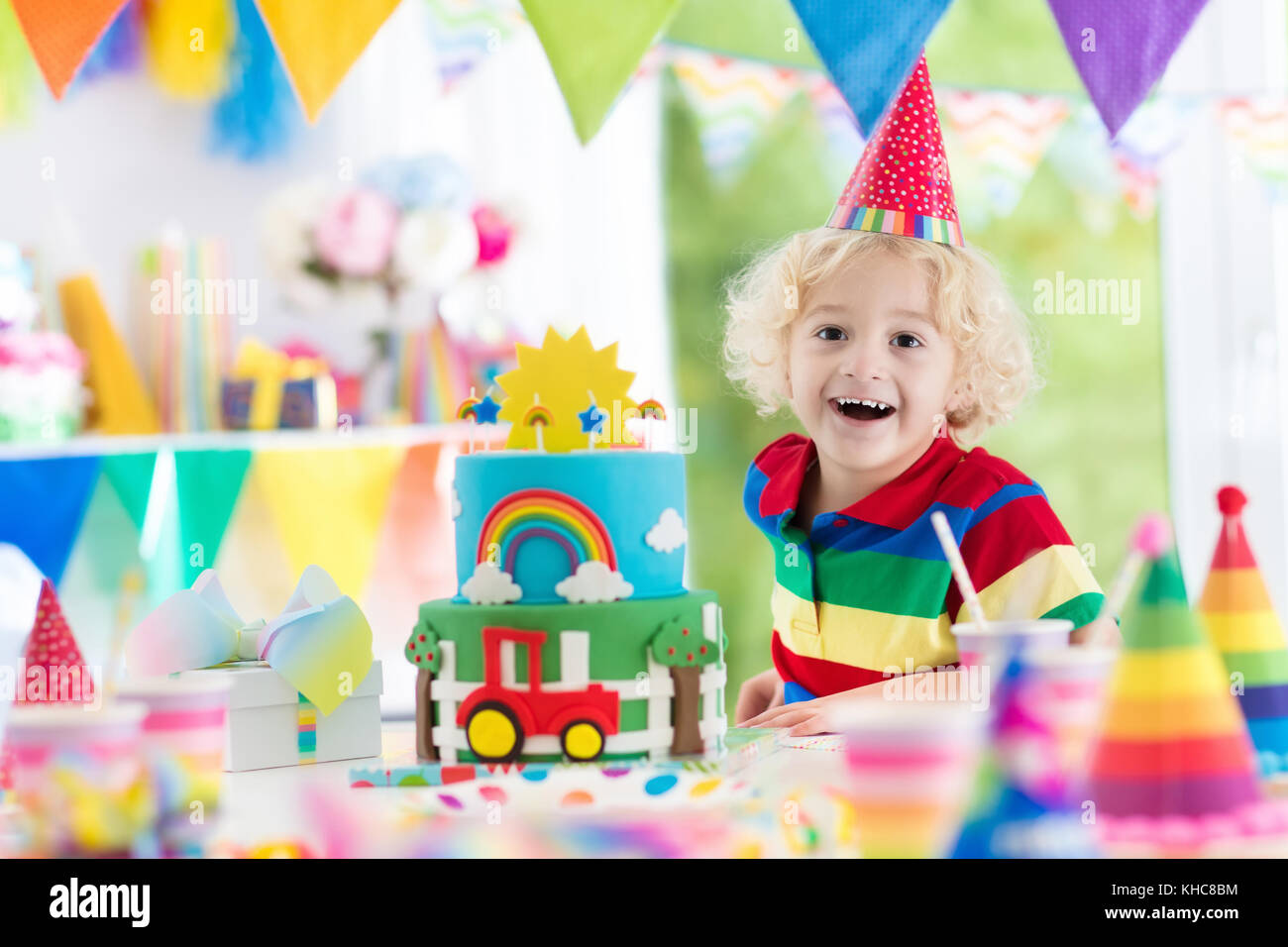 Fiesta De Cumpleanos Para Ninos Ninos Soplar Las Velas En Colores Pastel Decorado La Casa Con La Bandera Del Arco Iris Banderas Globos Granja Y Transporte Tema Celebrat Fotografia De Stock
