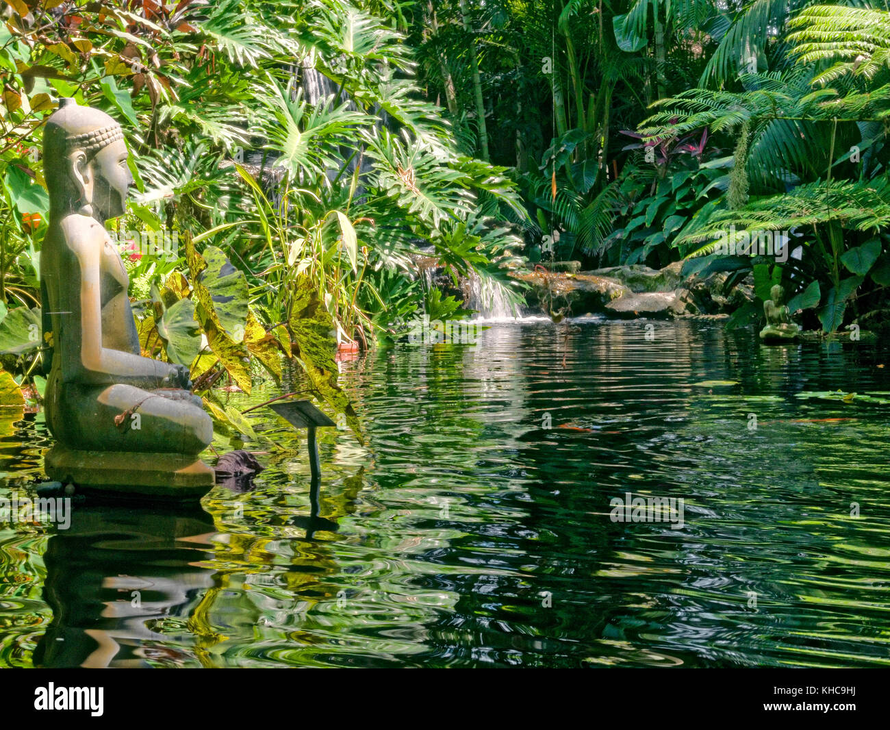 Escultura de bronce del Buda Gautama contemplando en meditación un estanque pequeño. Foto de stock