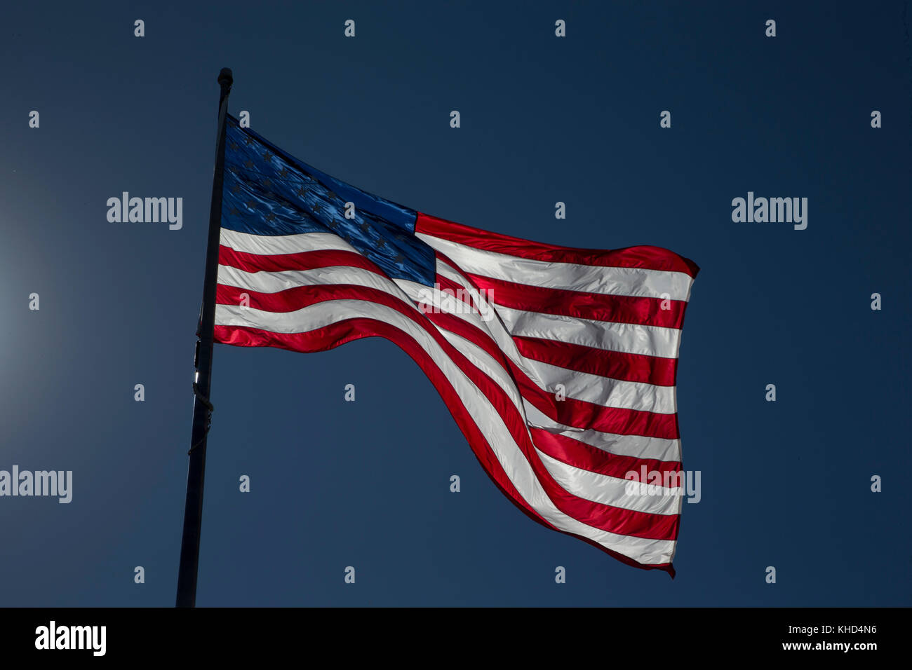 Retroiluminación de la bandera americana contra un cielo azul profundo Foto de stock