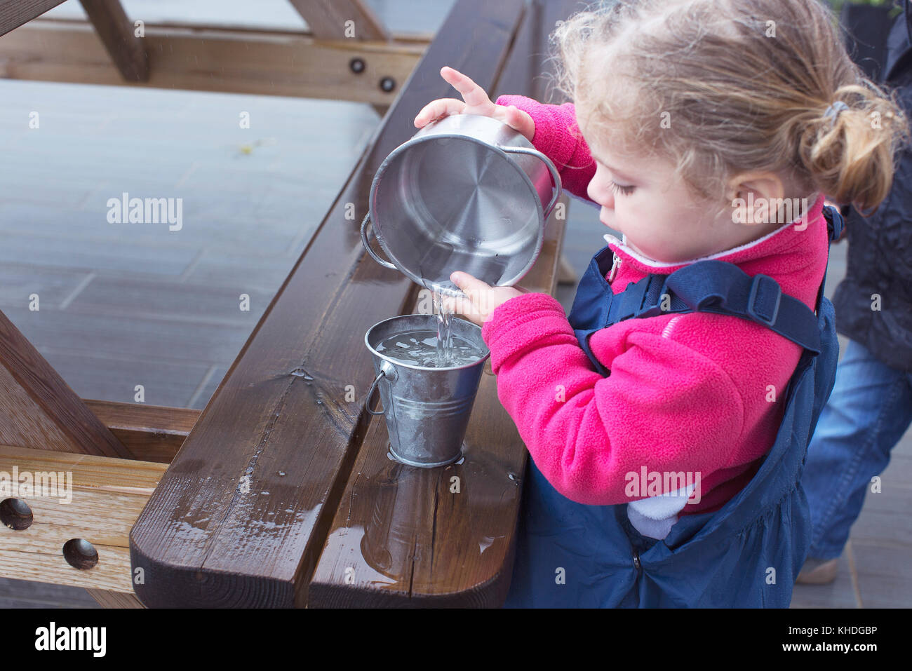 Pequeña niña vierte agua de un vaso a otro Stock Photo