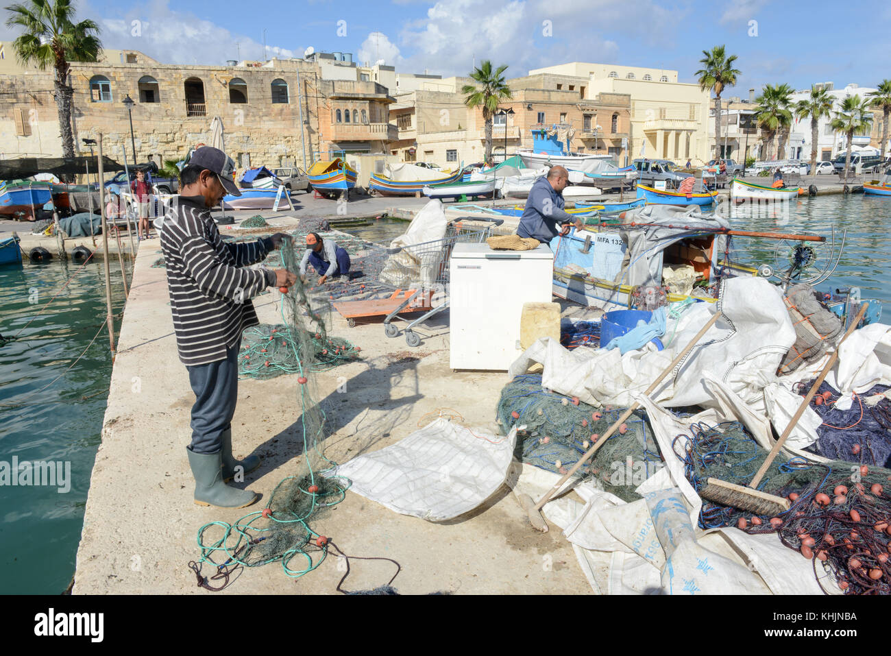 Marsaxlokk, Malta - 3 de noviembre de 2017: los pescadores preparando las redes de pesca cerca de su barco en Marsaxlokk en malta Foto de stock