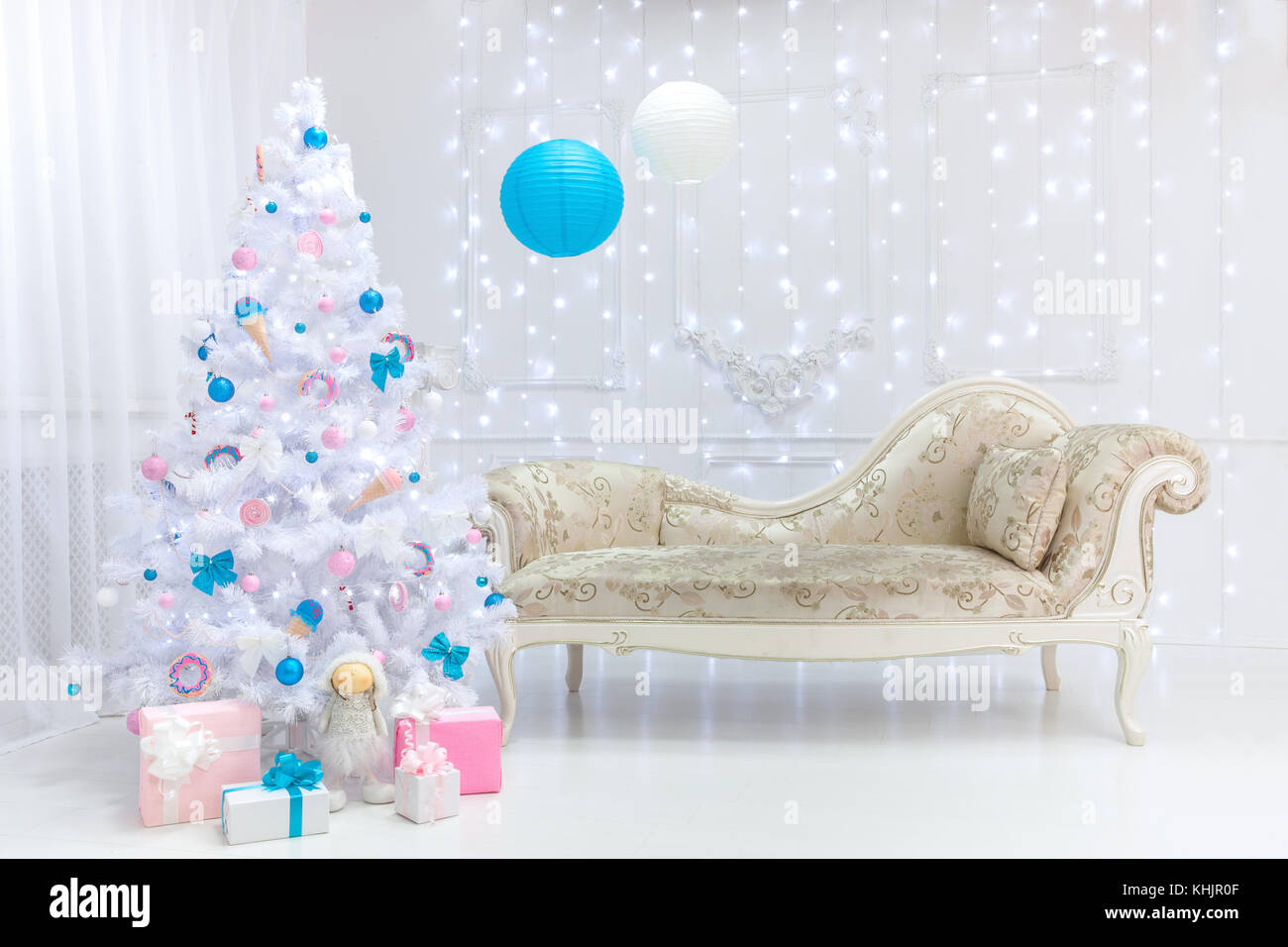 Luz de Navidad clásica interior en blanco, rosa y tonos de azul con un  sofá, un árbol y moldear en el estilo barroco y renacentista. grandes bolas  y don Fotografía de stock -