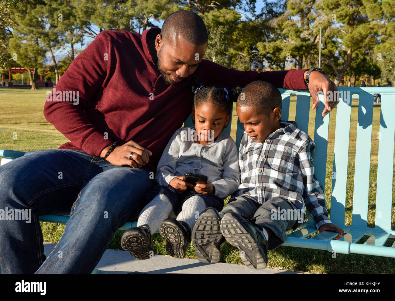 Padre afroamericano con hijo e hija en un parque. Foto de stock