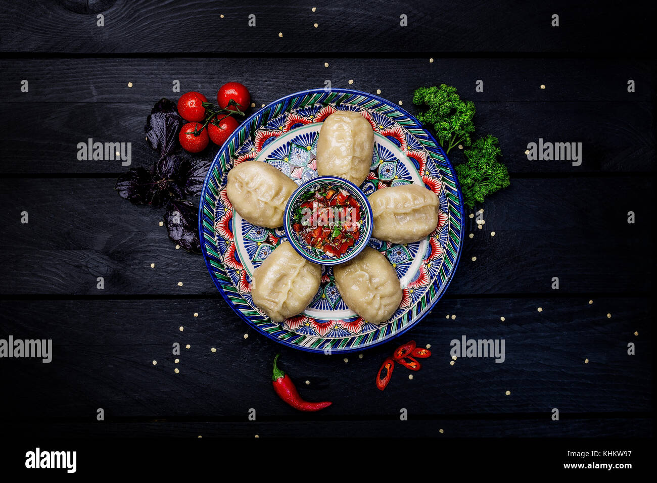 Los dumplings al vapor tradicional manti en placa con ornamento orientales con salsa de tomate. vista desde arriba. fondo de madera oscura. Foto de stock