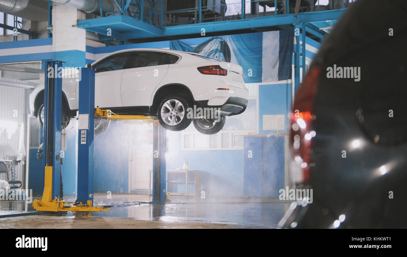 Mecánico en servicio de coche de lujo es el lavado suv debajo de la parte  inferior en el suds por mangueras de agua Fotografía de stock - Alamy