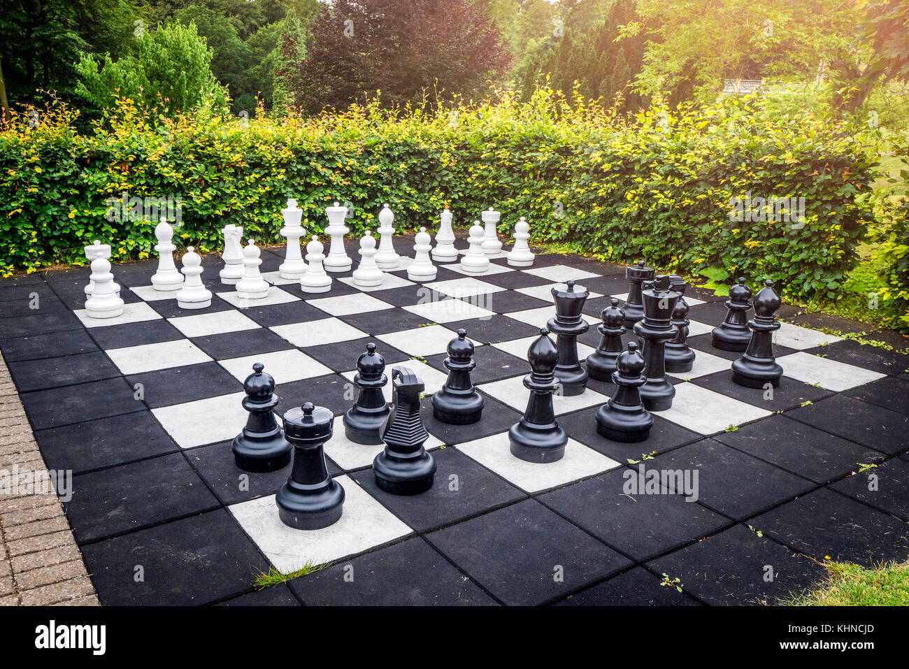 Gran juego de ajedrez al aire libre en un jardín con terraza en un patio  con un seto verde y el sol Fotografía de stock - Alamy