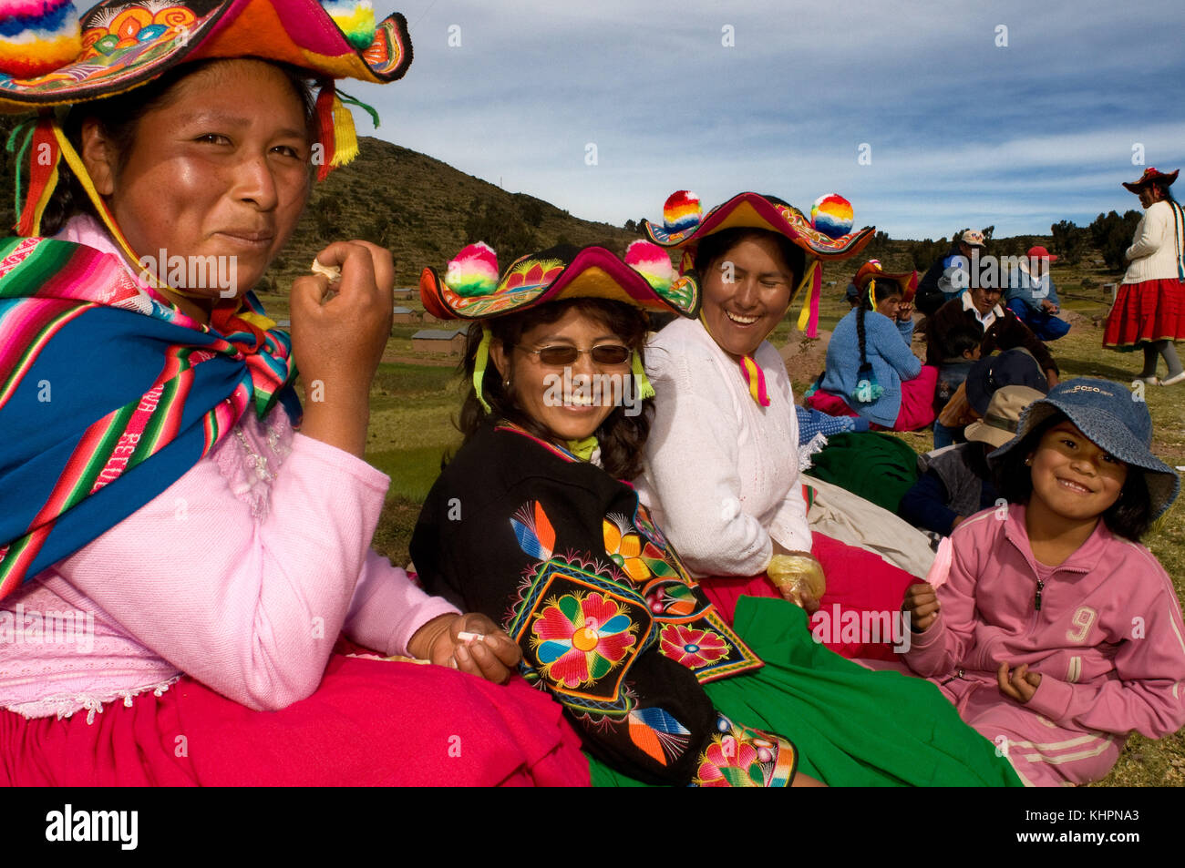 Varias mujeres de la aldea de llachón vestidas con el traje regional asistir a un partido de fútbol como público. La península de Capachica, cerca de Puno Foto de stock