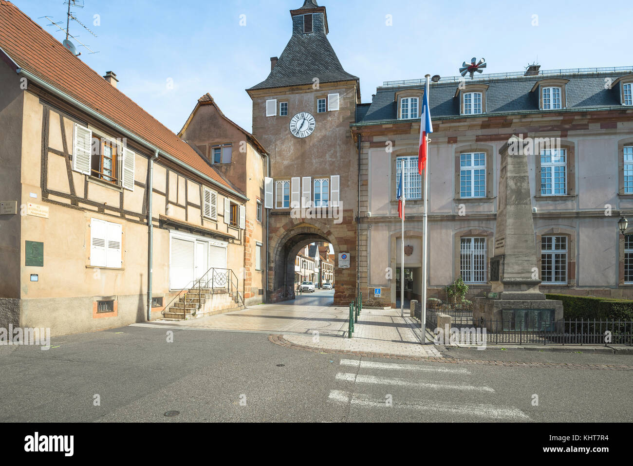 Cuadrado con la torre del reloj, banderas, puerta de la ciudad y el ayuntamiento del municipio rosheim, Alsacia, Francia Foto de stock