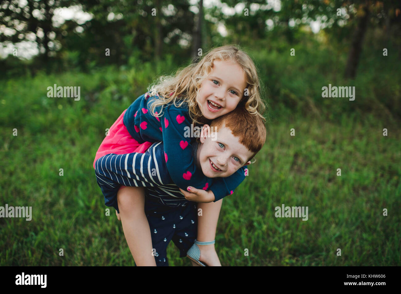 Retrato de niño dando hermana a cuestas en el campo Foto de stock