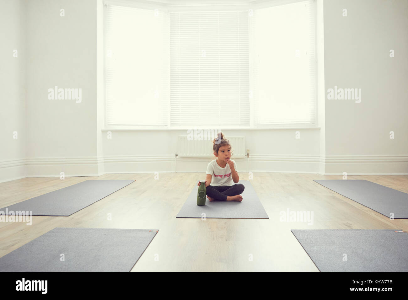 Joven en yoga studio, sentado sobre la estera del yoga Foto de stock