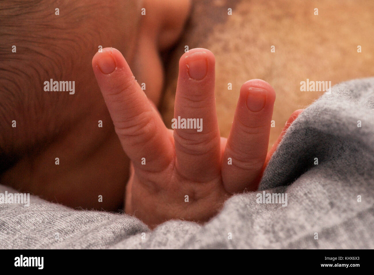 Bebé recién nacido mostrando tres dedos, quizás por tres leche? Foto de stock