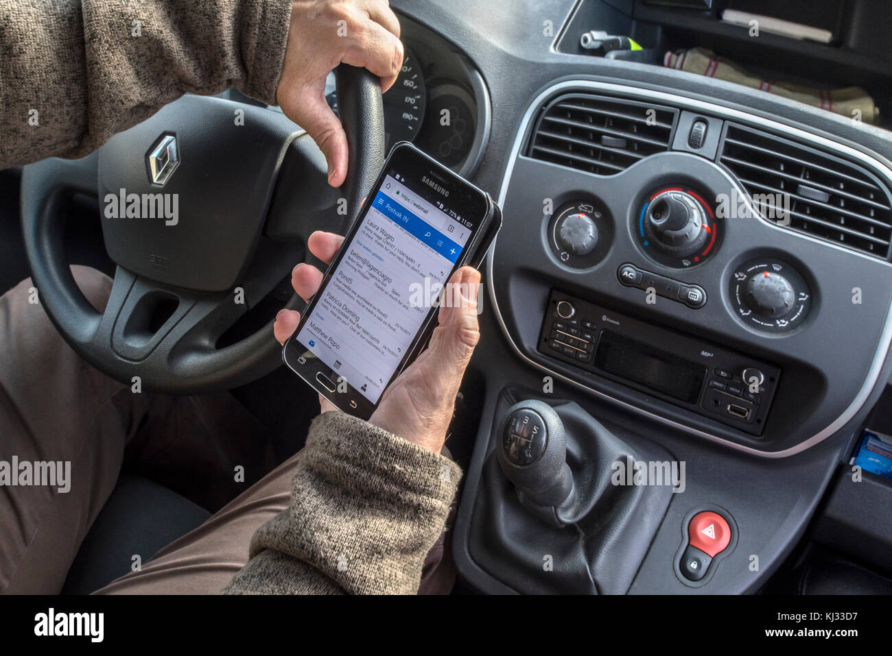 Hombre irresponsable al volante comprobando los mensajes en el teléfono inteligente / teléfono / teléfono móvil mientras se conduce el coche en la carretera Foto de stock