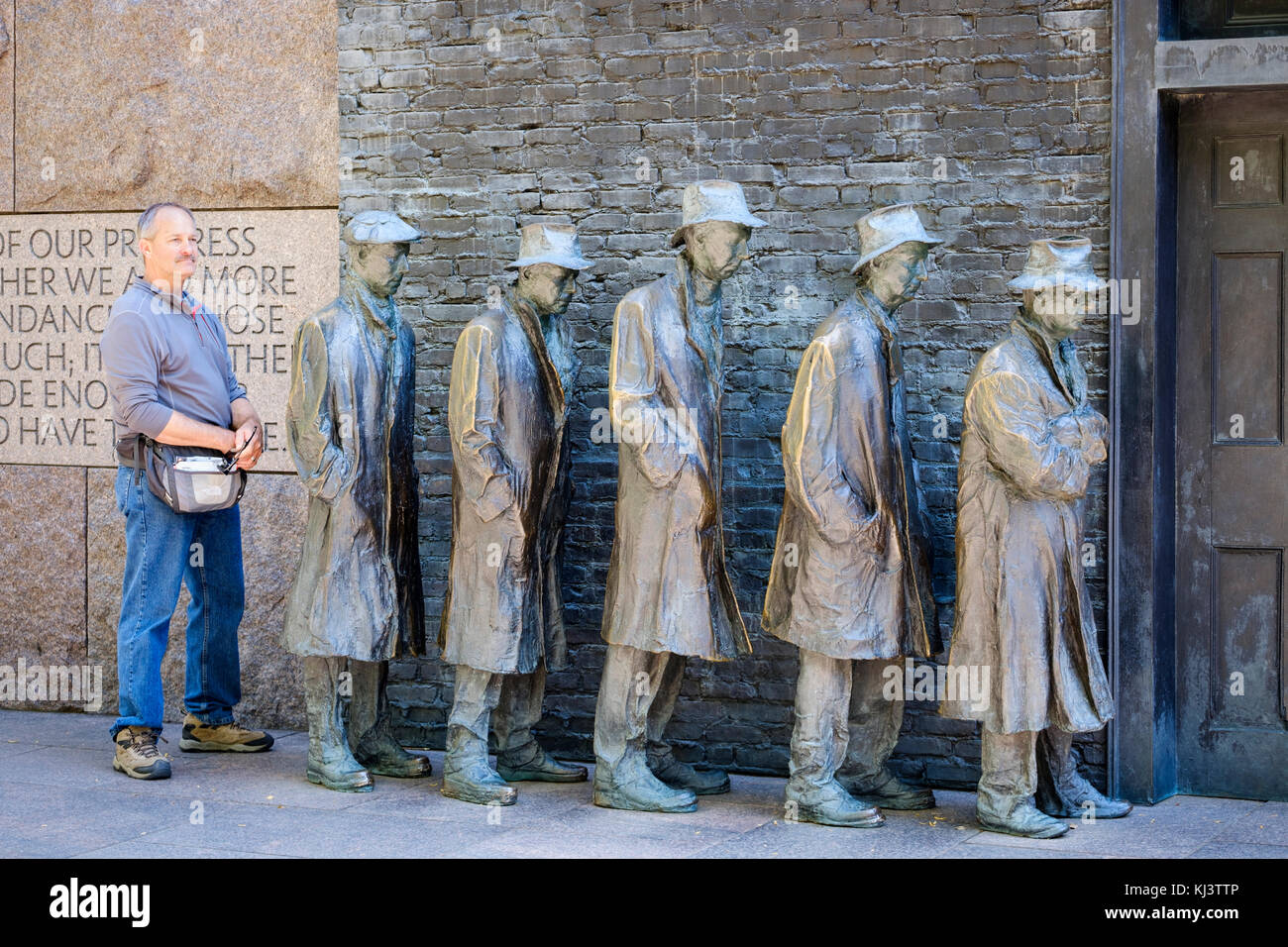 Un turista masculino posando para una foto en Bread Line, escultura de George Segal, Sala dos del Franklin Delano Roosevelt Memorial, Washington, D.C., EE.UU. Foto de stock