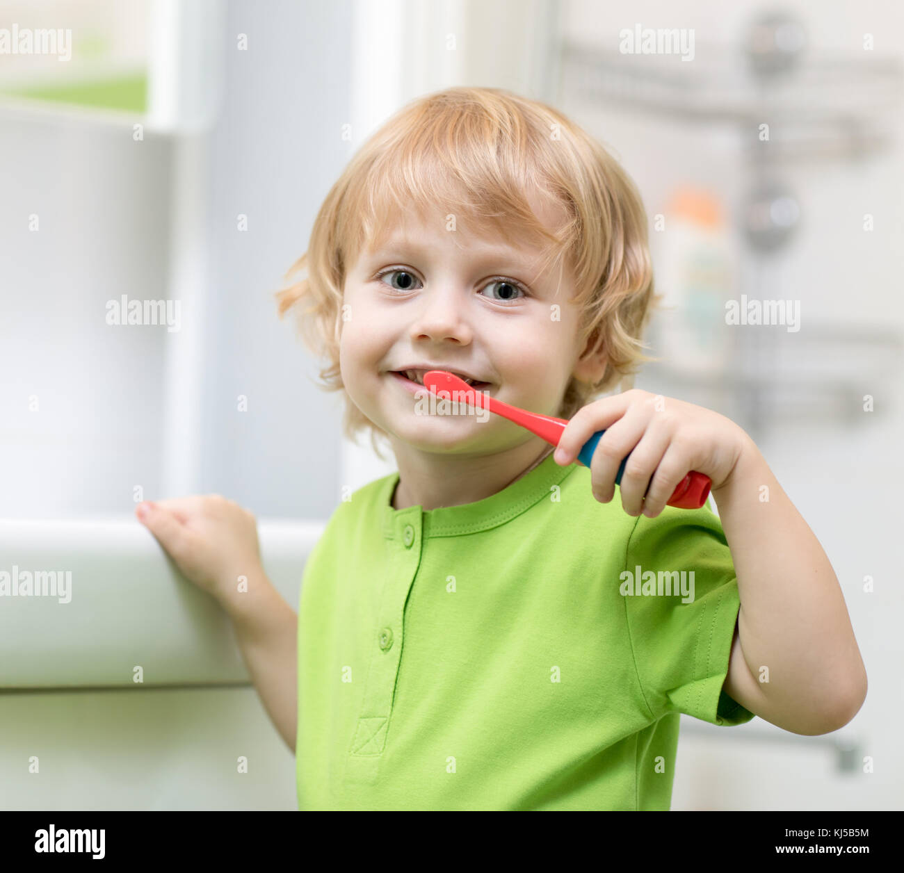 Niñito cepillando sus dientes en el baño. Foto de stock