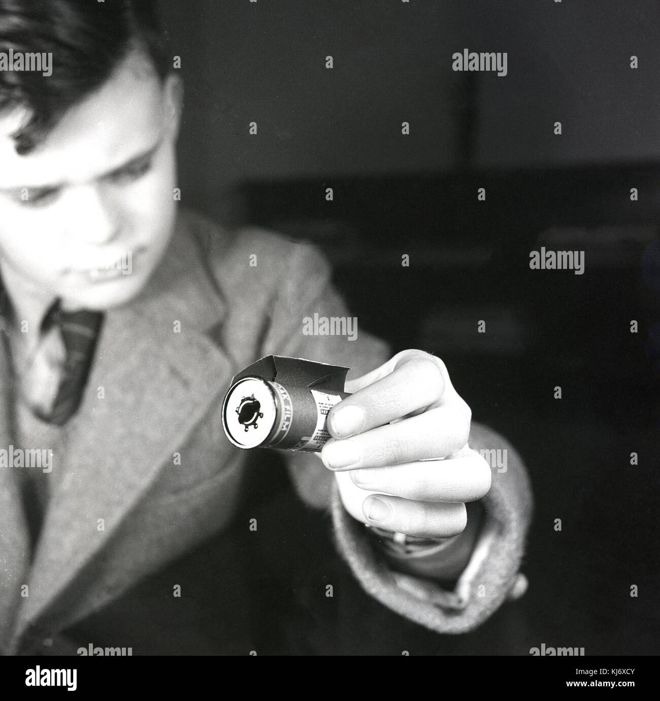 1950 histoical, niño sosteniendo un carrete de metal de rollo de Kodak Film (película) con refuerzo de papel para proteger la película de luz blanca. Rollo de película fue inventado en la década de 1880 y la patente presentada por Kodak. Foto de stock