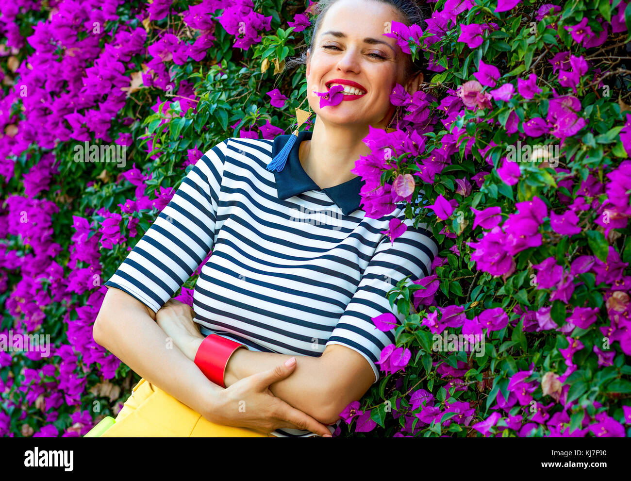 Colorida frescura. Retrato de mujer elegante y relajado en pantalones  cortos amarillos y camiseta de rayas creemos en la parte delantera de  coloridas flores magenta cama Fotografía de stock - Alamy