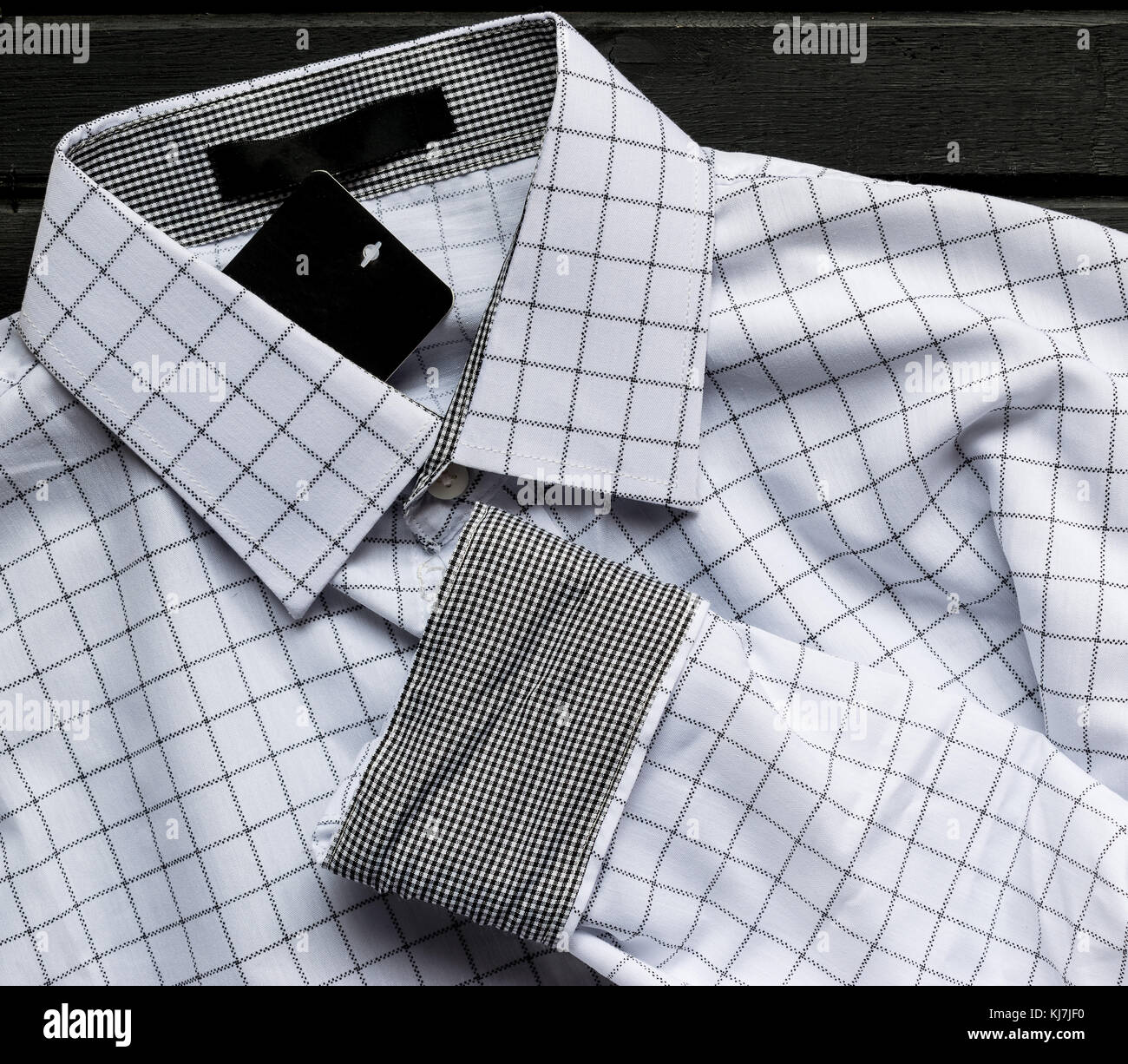 Los hombres camisa a cuadros pelado blanco, totalmente nueva, con etiquetas en la parte superior de la superficie de madera negra Fotografía de stock - Alamy