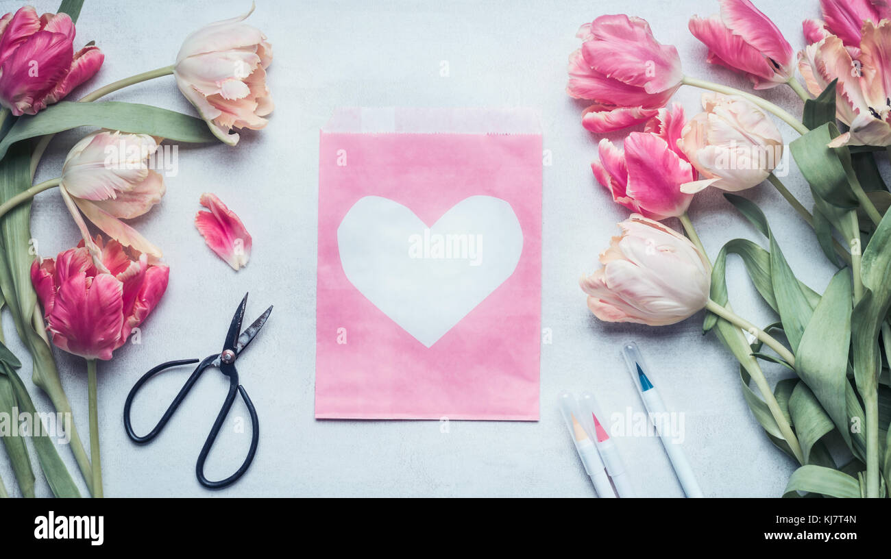 Preciosa maqueta de primavera color pastel con los tulipanes, tijeras,  marcadores y rosa pack bolsa de papel con el corazón , vista superior,  laicos plana Fotografía de stock - Alamy