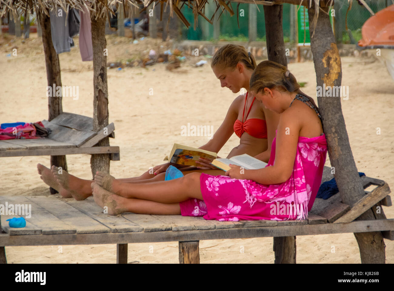 Dos niñas en el banco de madera en la playa de Trincomalee, Sri Lanka Foto de stock