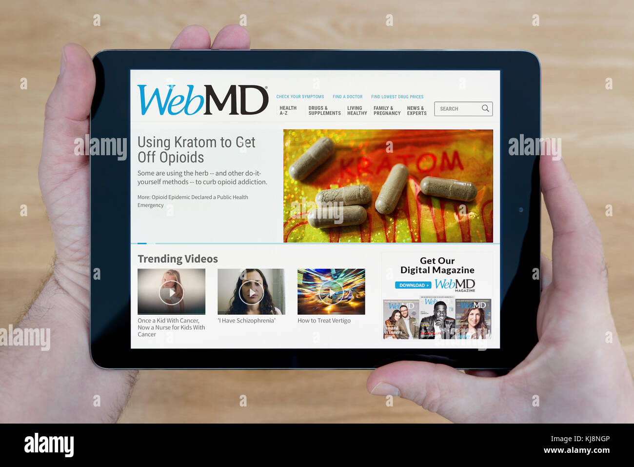 Un hombre mira el WebMD Portal sobre su dispositivo iPad, disparó contra una mesa de madera fondo superior (uso Editorial solamente) Foto de stock