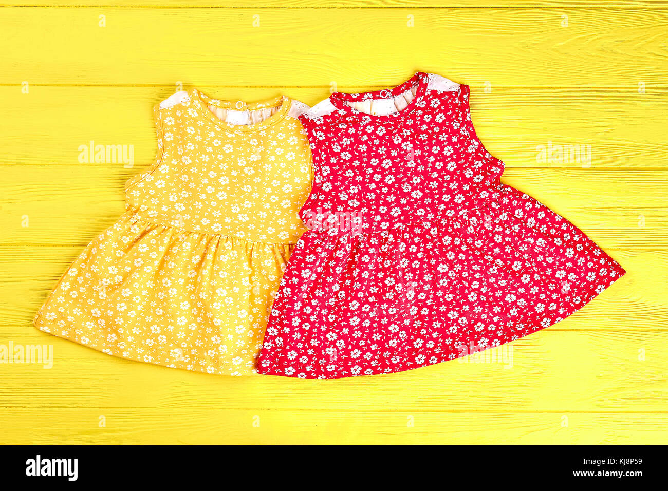 Conjunto de bonitos vestidos para bebés. niñas lactantes conjunto de  hermosos vestidos casual impreso en amarillo fondo de madera Fotografía de  stock - Alamy