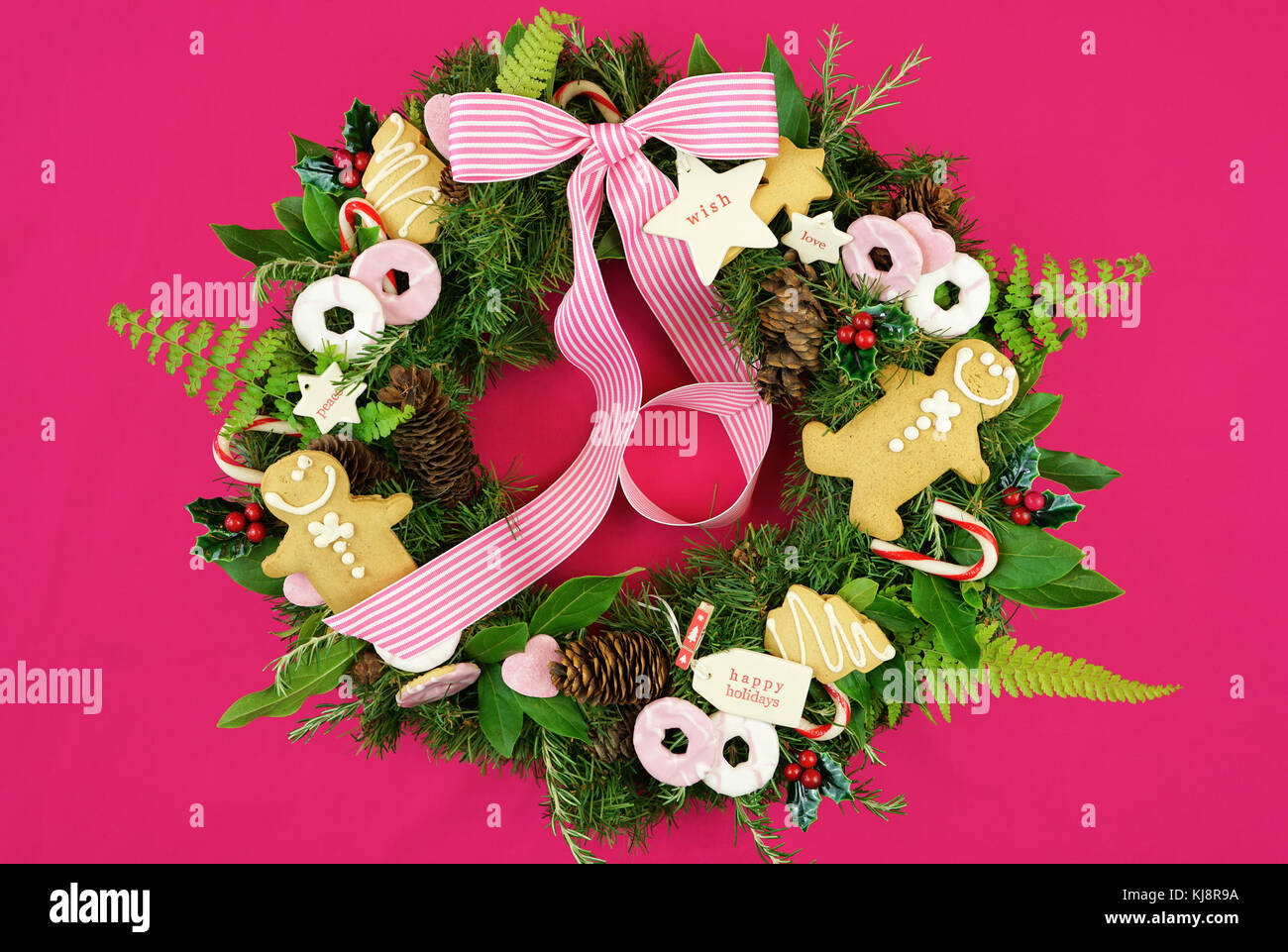 Corona Navideña con hierbas frescas, hojas, pan de jengibre, galletas,  dulces y las etiquetas del regalo, frente a la moderna tabla rosa brillante  Fotografía de stock - Alamy