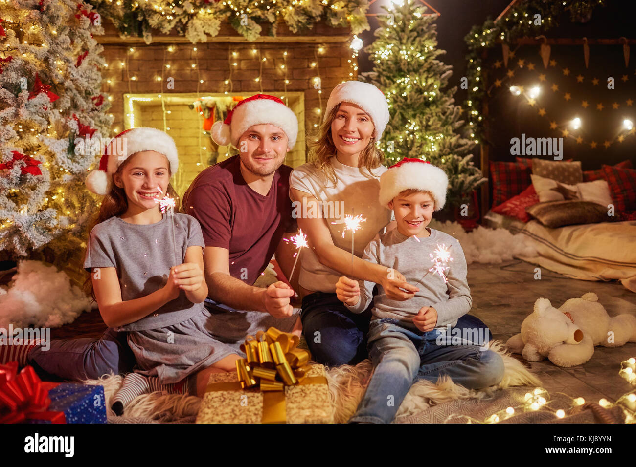 Familia con luces de bengala en la chimenea en la habitación el día de Navidad. Foto de stock