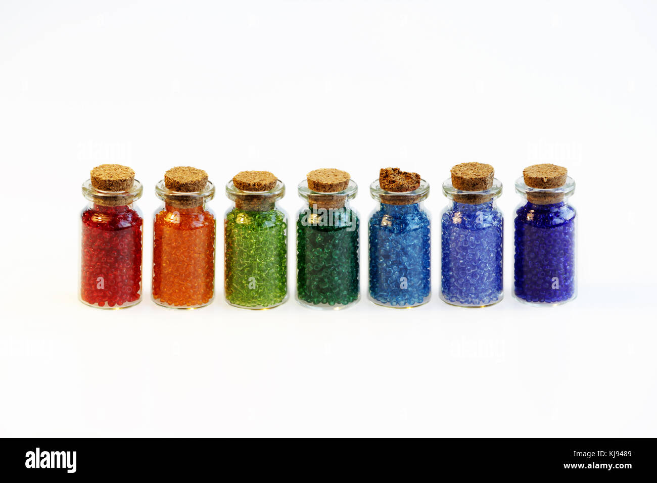 Siete pequeños frascos de vidrio con un tapón de corcho, lleno con un arco  iris de colores de cordones, sobre un fondo blanco Fotografía de stock -  Alamy
