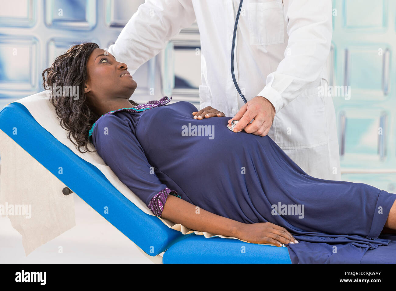 Guapo médico caucásico en bata blanca de consultoría es hermosa mujer embarazada africana en su oficina Foto de stock