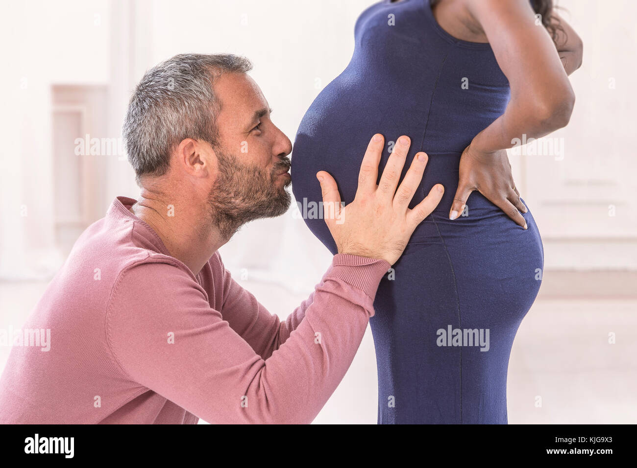 Mujer embarazada besarse con el amor de su marido, la sección abdominal del útero. El embarazo es de unos 8-9 meses Foto de stock