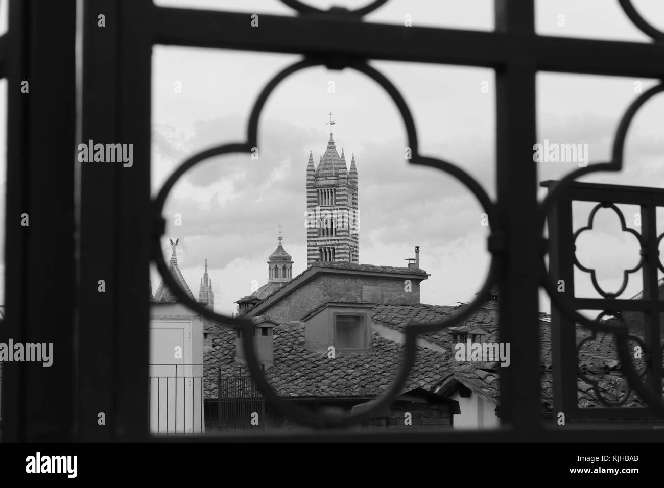 Vista de la torre de la catedral enmarcada por rejas. monocromo. de Siena, Italia. Foto de stock