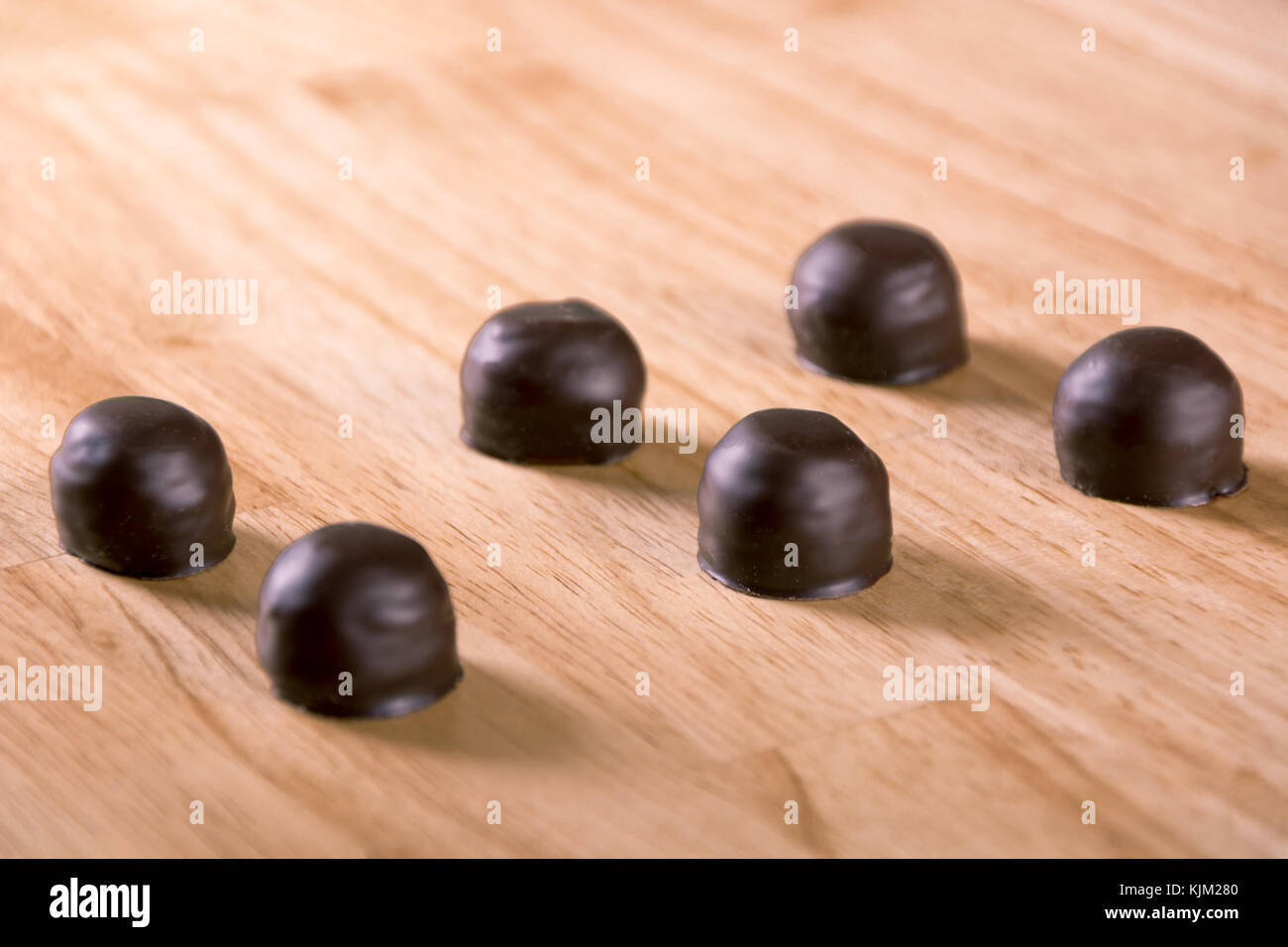 Juego de dark chocolate praliné bonbon sobre tabla de madera Foto de stock
